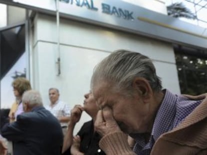 Um gerente do Banco Nacional da Grécia em Tessalônica explica a situação a um grupo de pensionistas que espera do lado de fora da agência.