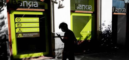 Una persona camina por el centro de Madrid delante de una sucursal de Bankia.