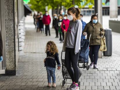 Una mujer y su hija hacen cola para comprar, en la plaza de Felipe II de Madrid.