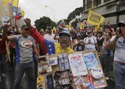 Un simpatizante opositor sostiene un cartel en el que exhibe los precios de los alimentos básicos en plena movilización contra Maduro en Caracas. La hiperinflación golpea con virulencia la economía venezolana desde hace años.