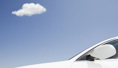 Un coche blanco bajo un cielo azul con una pequeña nube blanca.