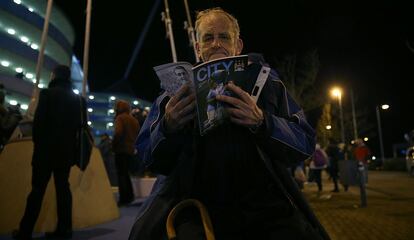 Un aficionado del Manchester City lee la revista oficial del club en los alrededores del estadio Etihad.