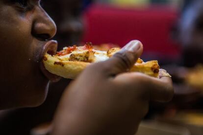 Homem come pizza em um restaurante dos EUA.