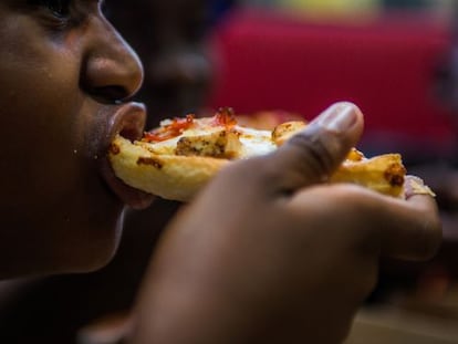 Homem come pizza em um restaurante dos EUA.
