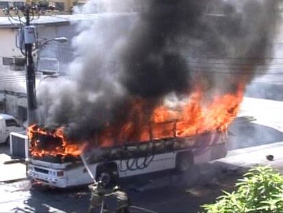 Los bombero intentan acabar con las llamas que envuelven al autobus.