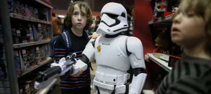 Unos niños muestran un muñeco de soldado de asalto imperial de la saga 'Star Wars' en una juguetería de Nueva York.