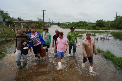 Un grupo de personas camina por una carretera inundada en Playa Majana, Cuba.