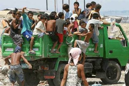 Unos niños filipinos se suben en un camión para ir a rebuscar entre la basura en Manila.