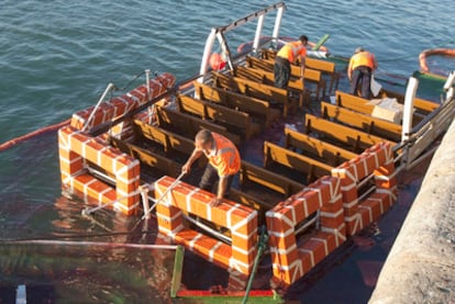 Dos personas encima de los restos del barco 'Adriano III', conocido como el 'Vaporcito', que hoy se ha hundido al chocar en el muelle de Cádiz