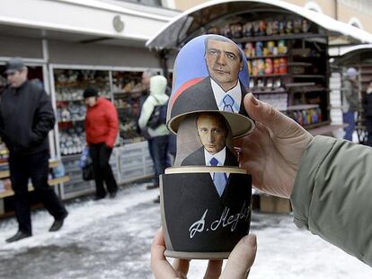 Un vendedor muestra una tradicional <i>matrioshka</i> rusa con los retratos de Dmitri Medvédev y Vladímir Putin en San Petersburgo.