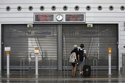 Unos viajeros permanecen en las puertas de una estación de metro cerrada durante la huelga en el aeropuerto Eleftherios Venizelos de Atenas, Grecia.