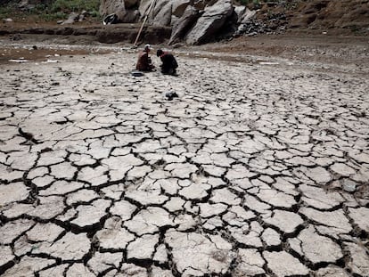 Dos personas sentadas en el lecho de un embalse afectado por la sequía en las afueras de Saná (Yemen), el 5 de junio de 2022.