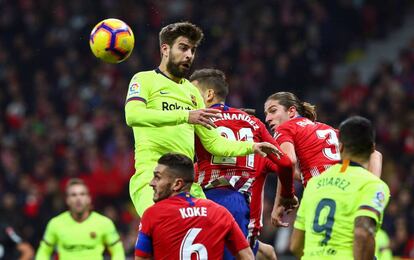 El defensa del FC Barcelona Gerard Piqué cabecea el balón ante jugadores del Atlético de Madrid.