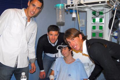 De izquierda a derecha, Pablo Prigioni, Xabi Alonso y Sergio Ramos, con un menor hospitalizado.