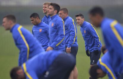 Mesut Ozil, en el medio de varios jugadores del Arsenal, estira durante el entrenamiento previo al partido de vuelta de los octavos de final que les enfrentará al Bayern de Múnich.