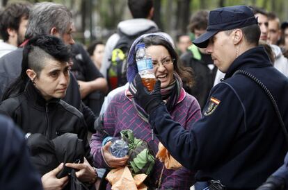 Un policía mira el líquido de una botella de plástico durante un registro de mochilas en las inmediaciones del Congreso de los Diputados. Madrid.