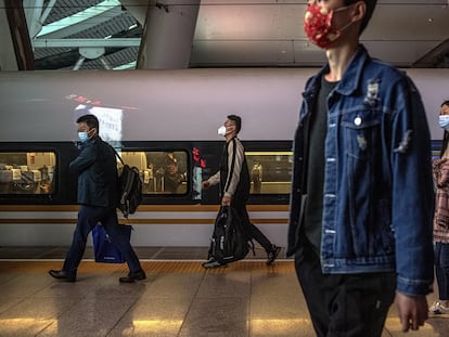 Varios pasajeros caminan por una estación de tren de Beijing.