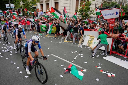 Ciclistas del Israel Premier-Tech ruedan frente a los protestantes en favor de Palestina.