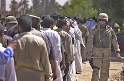 Un soldado estadounidense vigila que se respete el turno en una fila de ex soldados iraquíes que esperan para cobrar sus sueldos, en Bagdad.