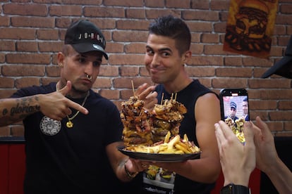 Javito, dueño del restaurante Black Bull y, a la derecha, Manuel Rodríguez, ganador del reto de engullir una hamburguesa de casi tres kilos, el pasado 18 de julio en Madrid.