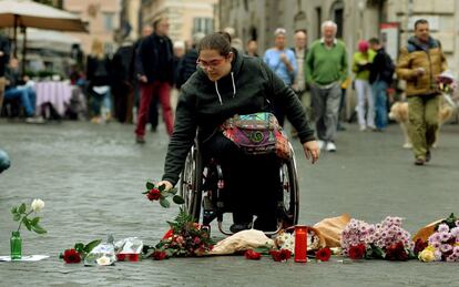 Una mujer en silla de ruedas deja flores en la plaza Farnesio, lugar donde se encuentra la Embajada de Francia en Roma (Italia).