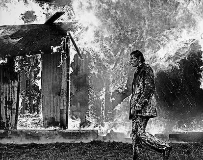 Un hombre camina ante un edificio ardiendo durante los 'Troubles' (National Library of Ireland).