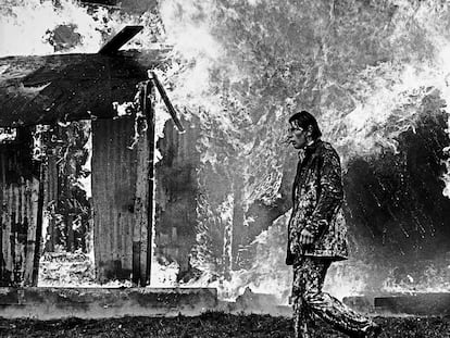 Un hombre camina ante un edificio ardiendo durante los 'Troubles' (National Library of Ireland).