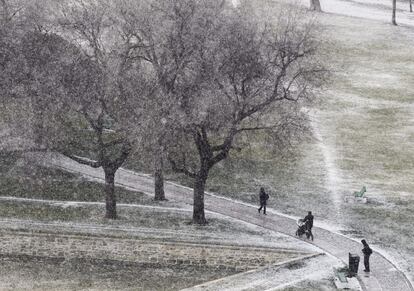 Varias personas pasean por el nevado parque de La Ciudadela, en el centro de Pamplona.