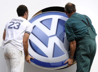 Dos trabajadores de Volkswagen colocan el logo de la empresa en la sede de Berlín.