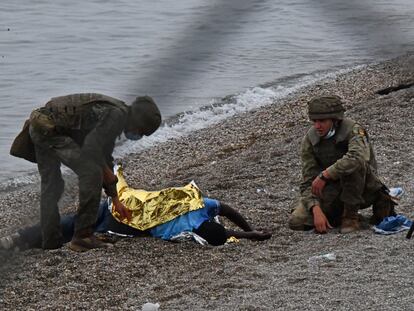 Dos soldados del Ejército de Tierra asisten a un inmigrante que acaba de llegar a la playa del Tarajal, el martes.