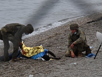 Dos soldados del Ejército de Tierra asisten a un inmigrante que acaba de llegar a la playa del Tarajal, el martes.