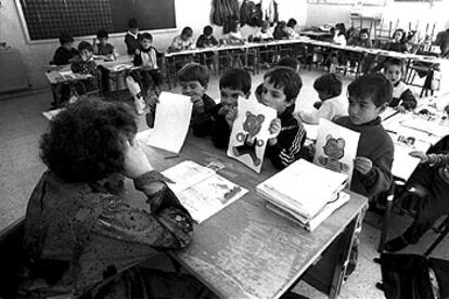 Unos ni?os ense?an sus dibujos a una profesora durante una clase.