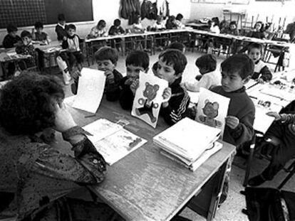 Unos niños enseñan sus dibujos a una profesora durante una clase.