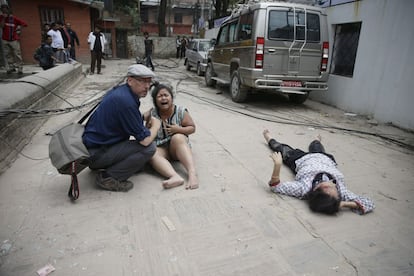 Un turista atiende a dos personas heridas tras el terremoto en Katmandú.