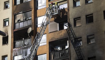 Los bomberos evacuan a vecinos del edifico quemado en Badalona. 