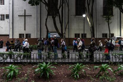 Decenas de personas esperan en una fila a recibir alimentos de forma gratuita en la Ciudad de México.