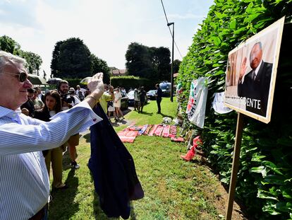 Un hombre hace una foto del retrato de Silvio Berlusconi, junto a la casa del ex primer ministro italiano.