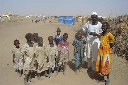 El jeque tribal Ahmed Abdell Alí escucha la radio con sus hijos en el campo de desplazados de Shangil Tobaya.