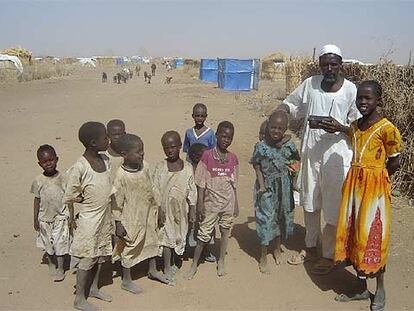 El jeque tribal Ahmed Abdell Alí escucha la radio con sus hijos en el campo de desplazados de Shangil Tobaya.