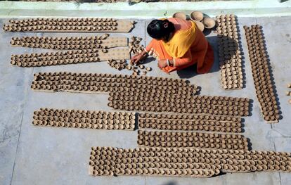 Una mujer india, en su taller casero, coloca unas velas de barro artesanales para secarlas al sol para el próximo festival de Diwali en Jammu, capital invernal de Cachemira, India.