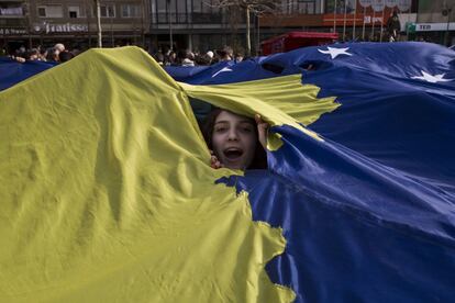 Una niña de Kosovo mira a través de una bandera gigante de Kosovo que se exhibe durante la celebración del noveno aniversario de la independencia en la capital Pristina (Kosovo). Kosovo declaró la independencia de Serbia el 17 de febrero de 2008 y hasta ahora ha sido reconocido por 113 países, incluyendo Estados Unidos y una mayoría de miembros de la Unión Europea.