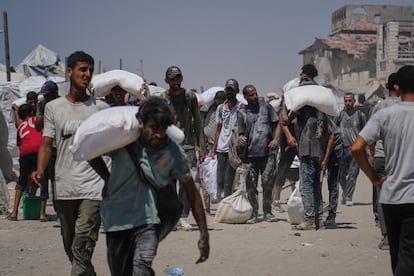 Decenas de palestinos cargan con sacos descargados de un convoy de ayuda humanitaria en Ciudad de Gaza, este domingo.