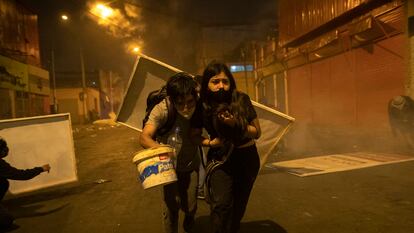 Dois jovens manifestantes procuram abrigo depois que a polícia os dispersou com gás lacrimogêneo em 14 de novembro.