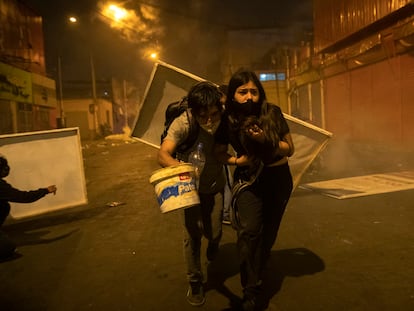 Dois jovens manifestantes procuram abrigo depois que a polícia os dispersou com gás lacrimogêneo em 14 de novembro.