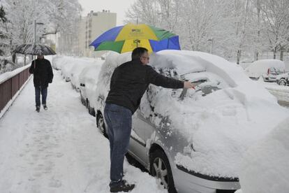 Un vecino de Vitoria retira la nieve acumulada en su vehículo.