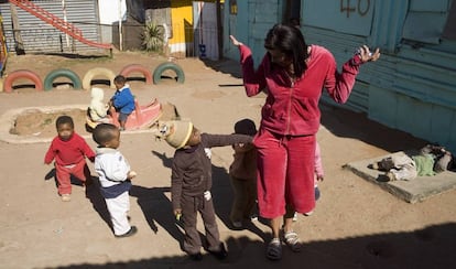 Unos niños buscan en los bolsillos de una visitante a un jardín de infancia de Soweto.