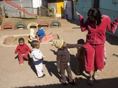 Crianças xeretam os bolsos de uma visitante em um jardim da infância de Soweto.