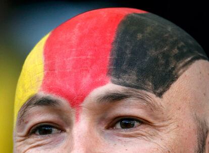 Un seguidor alemán, con la cabeza pintada con la bandera de su país, anima a su selección.