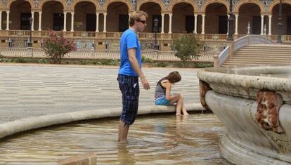 Unos turistas se refrescan en la Plaza de Espa&ntilde;a de Sevilla.