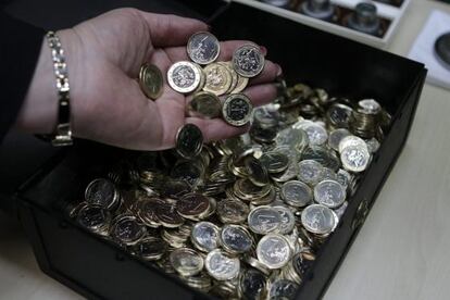 Una mujer sostiene varias monedas de euro recién acuñadas.